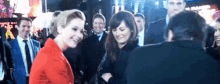 a woman in a red jacket is standing next to another woman in a crowd .