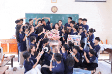 a group of students are posing for a picture in front of a blackboard that says ' a ' on it