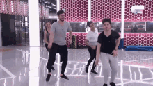 a group of people are dancing in a room with a pink wall .