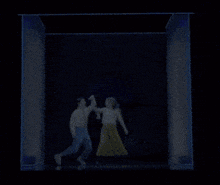 a man and a woman are dancing in a room with blue lights