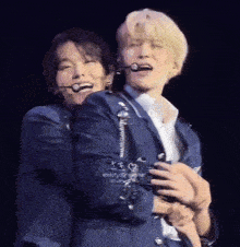 a man in a suit is hugging another man in a white shirt on a stage .