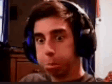 a young man wearing headphones making a funny face .