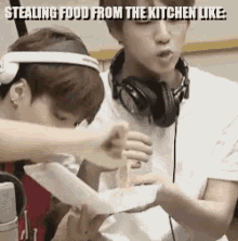 two young men wearing headphones are stealing food from the kitchen like