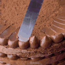 a chocolate cake is being frosted with a spatula and the word mr.cakes is visible in the corner