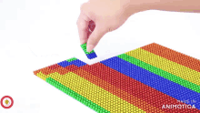 a person is playing with a rainbow colored bead mat made by animatica
