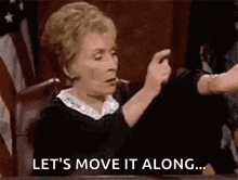 a judge is sitting at a table in a courtroom giving a thumbs down sign .