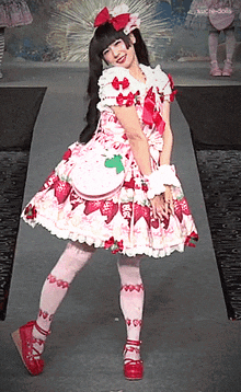 a woman in a strawberry dress is walking down a runway