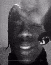 a black and white photo of a man with his eyes closed and a peace sign on his face