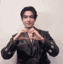 a man in a black leather jacket making a heart shape with his hands