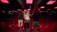 a woman in a white tank top is dancing with a man and woman