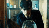 a man in a suit and tie is looking at a glass globe .