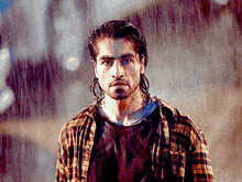 a man in a plaid shirt is standing in the rain with the word jani in the corner