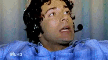 a man in a blue shirt is laying in a hospital bed with a microphone on his head and the word hd on the bottom left