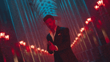 a man in a tuxedo is holding a lighter in a dark room