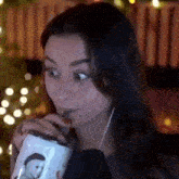 a woman is drinking a drink through a straw while wearing headphones .
