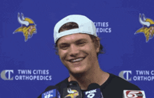 a man wearing a white hat is smiling in front of a blue backdrop that says twin cities orthopedics