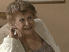 an elderly woman wearing a white jacket is talking on a cell phone and smiling