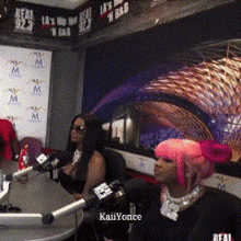 a woman with pink hair is sitting at a table in front of a microphone with the name kaiiyonce on the bottom