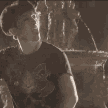 a man in a black shirt is standing in front of a fountain in a dark room .