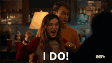 a woman says i do in front of a man and a bet logo