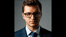 a man wearing glasses and a suit and tie looks at the camera