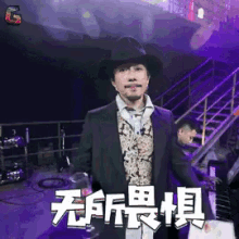a man in a suit and hat is standing in front of a stage with chinese characters on it