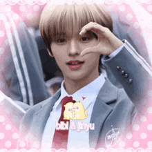 a boy in a suit and tie making a heart with his hands and the words bibi & jinyu
