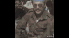 a man in a military uniform with a mustache and sunglasses is sitting down .