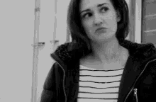 a woman in a striped shirt and a black jacket is making a funny face .