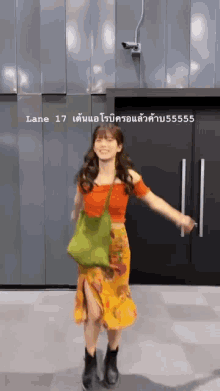 a woman in an orange top and yellow skirt is dancing in front of a door with the number 17 on it