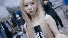 a woman with long blonde hair is wearing a black tank top and a microphone in her hand .