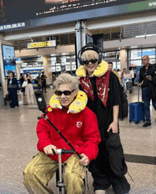 a man wearing headphones stands next to another man wearing a red jacket