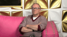 a man sitting on a pink couch with his arms crossed