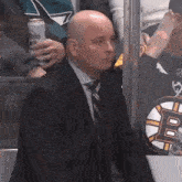 a man in a suit and tie is sitting in a hockey stadium holding a can of modelo beer .