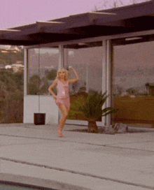 a woman in a pink dress stands in front of a building