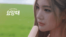 a woman is holding an ice cream cone in front of a field with chinese writing on it