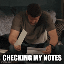 a man is checking his notes while sitting on a bed