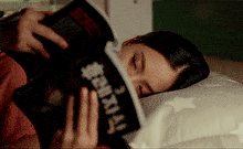 a woman laying on a bed reading a book with chinese writing on it