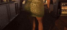a woman in a green dress is standing in a kitchen