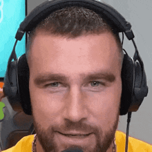a man with a beard wearing headphones and a yellow shirt