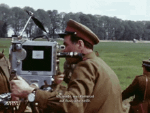a man in a military uniform holds a camera and says ich lernte was kamerad