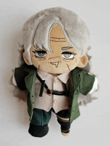 a stuffed doll with gray hair is wearing a green jacket and white shirt