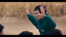 a man in a green jacket is giving a high five to another man .