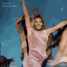 a man in a pink dress is dancing in front of a blue background with the words made with reface app