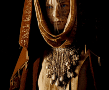 a woman with a scarf around her head has a tattoo on her face that says ' a ' on it