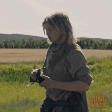 a poster for the long walk shows a woman holding a camera in a field