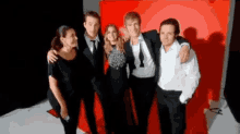 a group of people posing for a photo in front of a red background