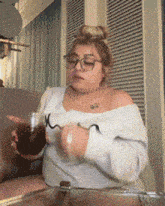 a woman wearing glasses is sitting on a couch and holding a glass of wine
