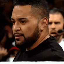 a man with a beard wearing a black shirt is standing in a crowd