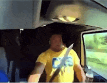 a man wearing a yellow shirt that says cs is sitting in a car